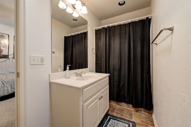 ensuite bathroom featuring vanity, a textured wall, a shower with shower curtain, stone finish floor, and ensuite bath