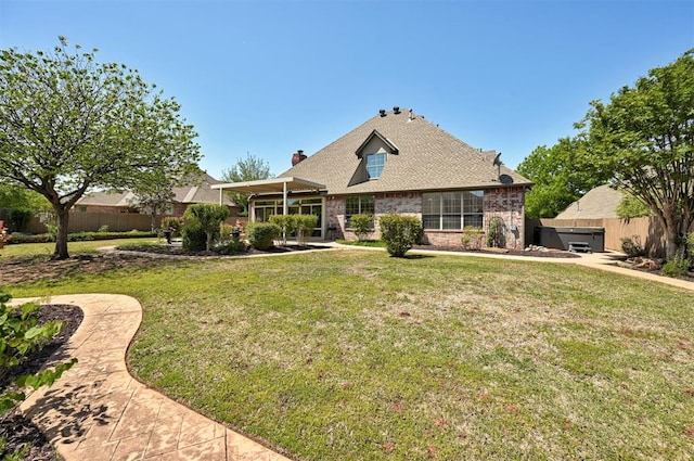 view of front of home with a front lawn, fence, a chimney, brick siding, and a hot tub