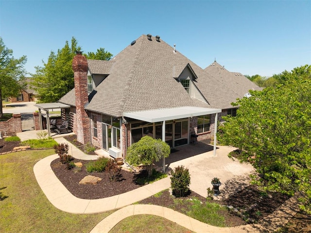rear view of house featuring a sunroom, a chimney, and roof with shingles