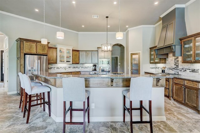 kitchen featuring a breakfast bar area, appliances with stainless steel finishes, a large island with sink, and tasteful backsplash