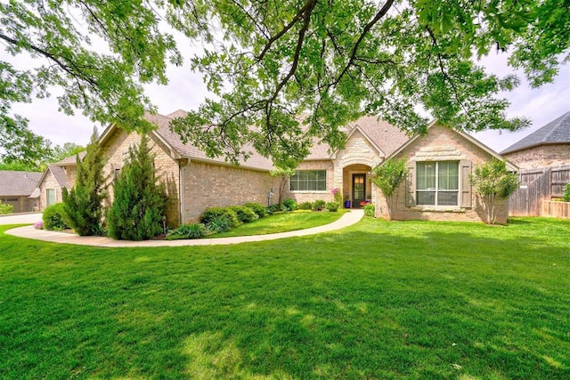 view of front of house featuring brick siding, fence, stone siding, and a front yard
