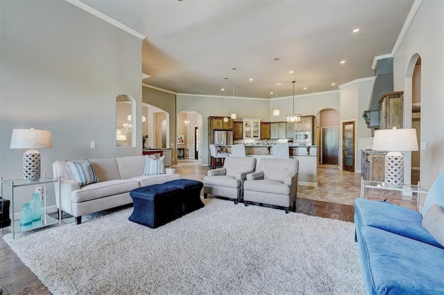 living room with crown molding, arched walkways, recessed lighting, and light wood finished floors