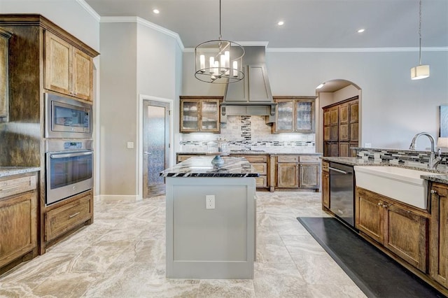 kitchen featuring crown molding, appliances with stainless steel finishes, a sink, arched walkways, and backsplash