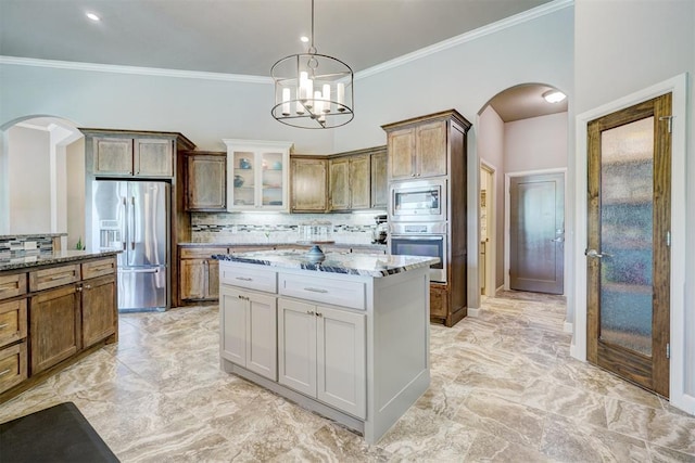 kitchen with stone countertops, arched walkways, backsplash, and stainless steel appliances
