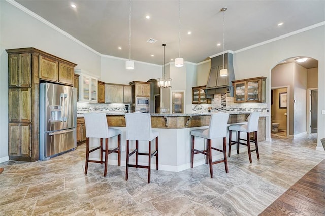 kitchen featuring arched walkways, stainless steel appliances, custom range hood, backsplash, and ornamental molding