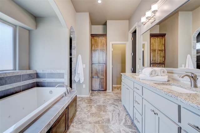 full bathroom with a tub with jets, a sink, and double vanity