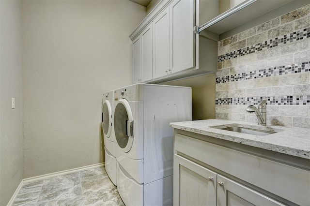 clothes washing area with a sink, baseboards, cabinet space, and washing machine and clothes dryer