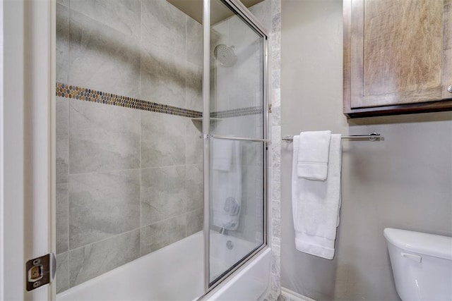 bathroom with bath / shower combo with glass door and toilet