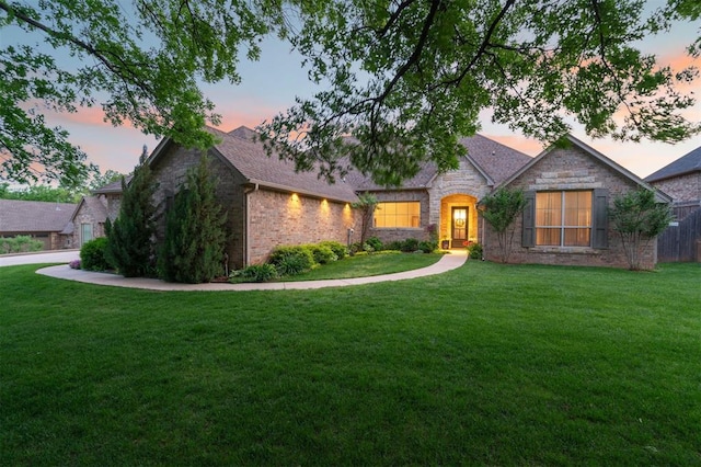 view of front of home featuring brick siding, stone siding, and a front lawn
