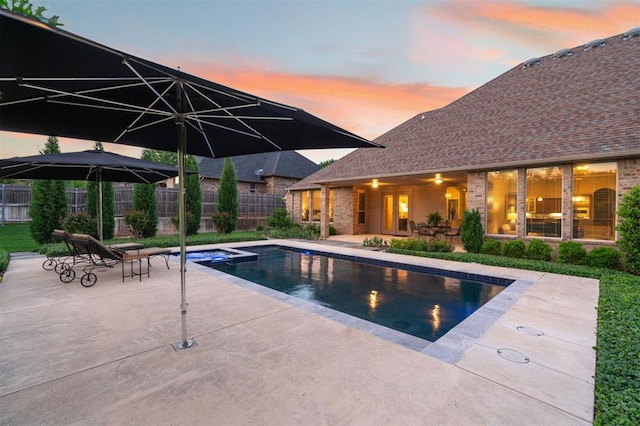 view of swimming pool featuring a pool with connected hot tub, fence, and a patio area