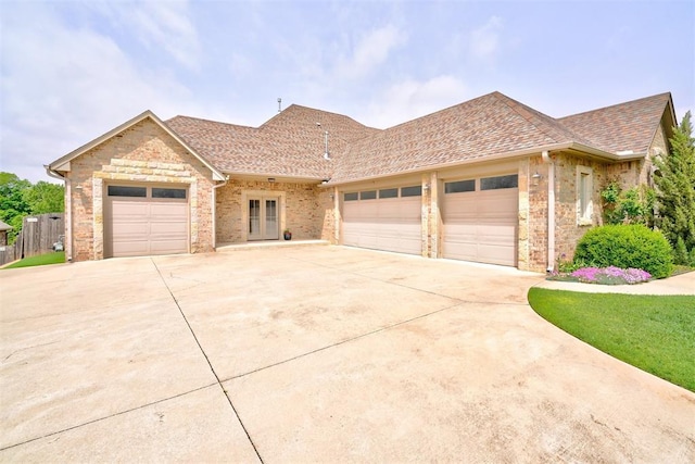 ranch-style home featuring a shingled roof, an attached garage, driveway, and brick siding