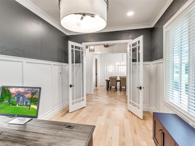 hall featuring french doors, wainscoting, a decorative wall, and light wood-type flooring