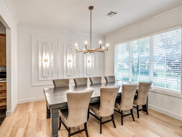 dining area featuring visible vents, crown molding, baseboards, an inviting chandelier, and light wood-style flooring