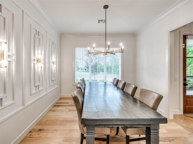 dining space with a chandelier, baseboards, light wood-type flooring, visible vents, and ornamental molding
