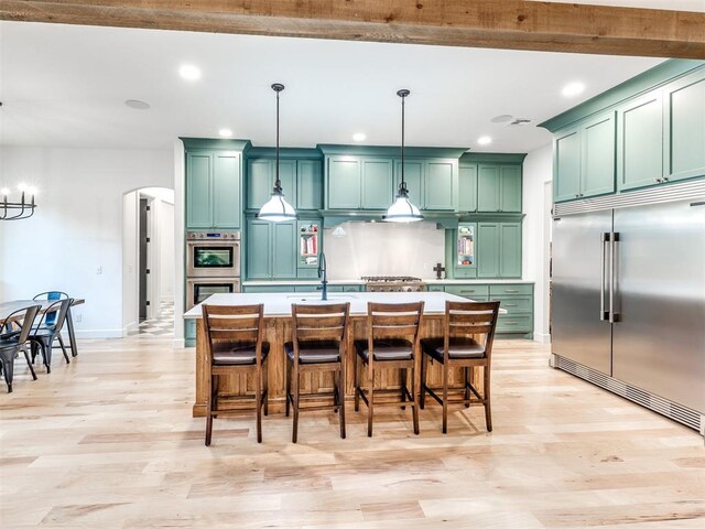 kitchen featuring light wood-style floors, green cabinets, stainless steel appliances, and recessed lighting
