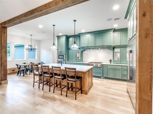 kitchen with light countertops, appliances with stainless steel finishes, green cabinetry, and light wood-style floors