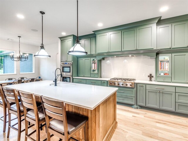 kitchen featuring a sink, appliances with stainless steel finishes, green cabinets, and a kitchen bar