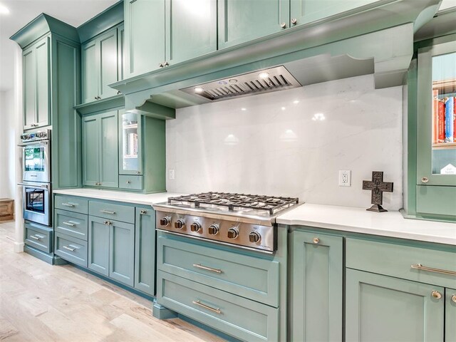 kitchen featuring light countertops, appliances with stainless steel finishes, green cabinets, and under cabinet range hood