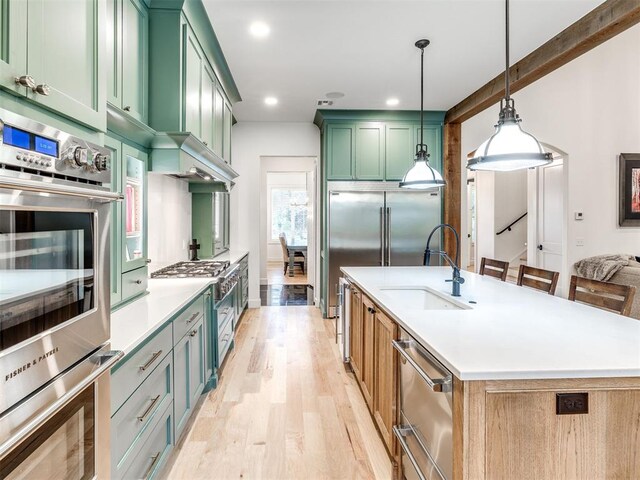 kitchen with a sink, light wood-style flooring, green cabinets, and light countertops