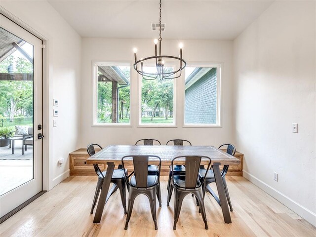dining room featuring baseboards, a chandelier, visible vents, and light wood-type flooring