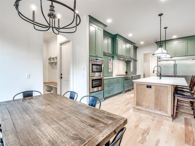 kitchen featuring stainless steel double oven, hanging light fixtures, light countertops, green cabinets, and light wood finished floors