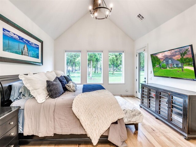 bedroom with light wood-style floors, multiple windows, visible vents, an inviting chandelier, and access to outside