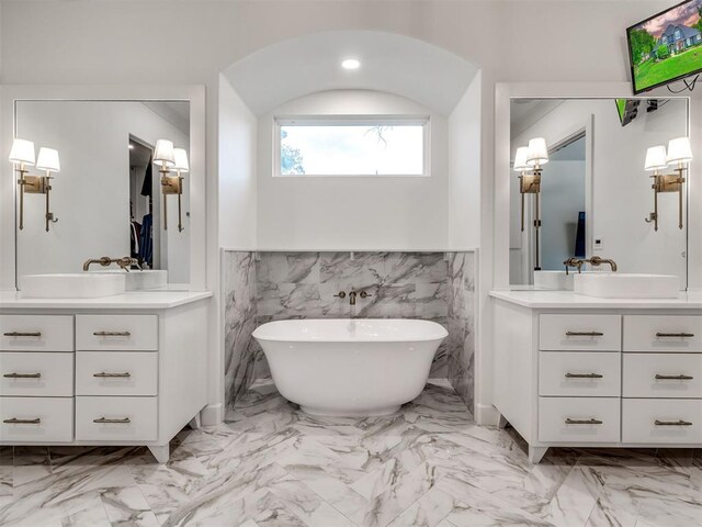 full bathroom featuring a sink, marble finish floor, a freestanding bath, and two vanities