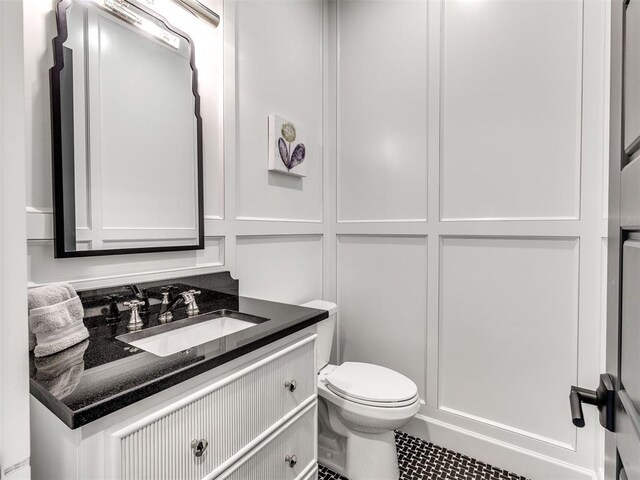 half bathroom featuring vanity and toilet