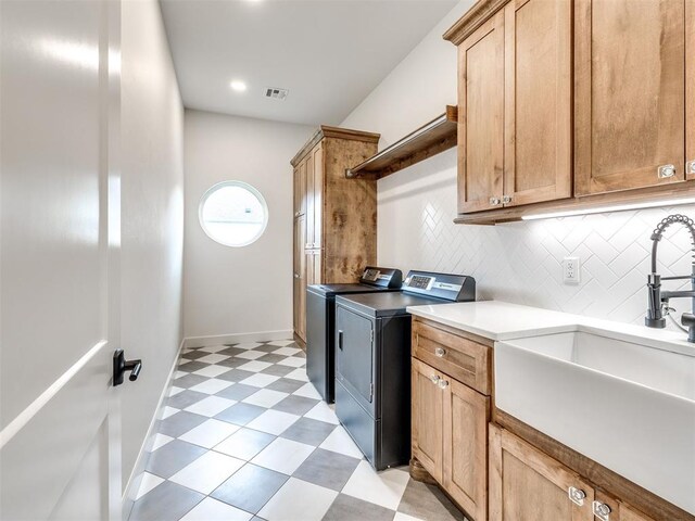 laundry room with visible vents, light floors, washer and clothes dryer, a sink, and cabinet space
