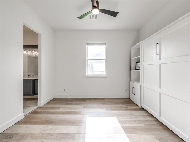unfurnished bedroom featuring baseboards, visible vents, ensuite bathroom, and light wood-type flooring