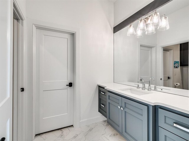 bathroom with vanity, marble finish floor, and baseboards
