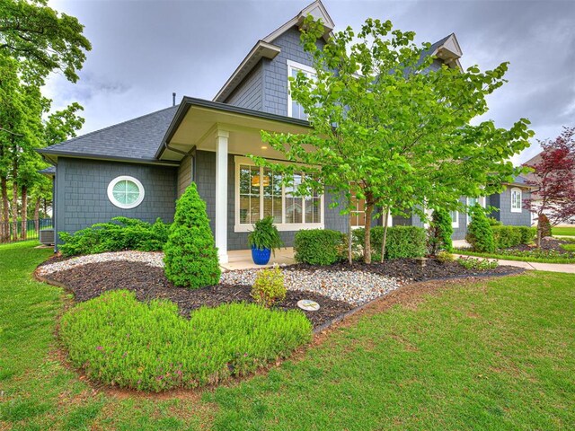 view of front of house with a shingled roof and a front yard