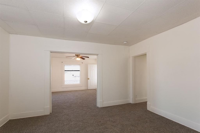 carpeted empty room featuring baseboards, ceiling fan, and a paneled ceiling