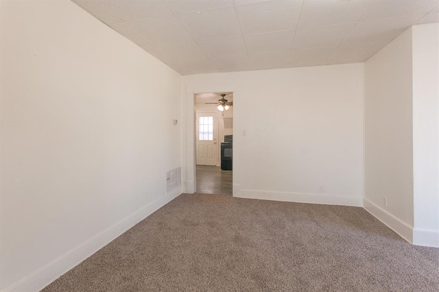 carpeted empty room featuring baseboards, ceiling fan, and visible vents