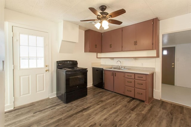 kitchen featuring light countertops, a sink, black appliances, and dark wood-type flooring