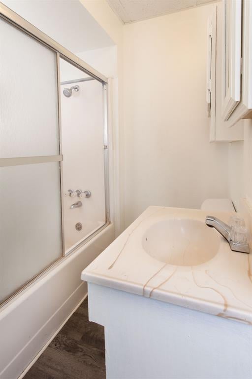full bath featuring vanity, wood finished floors, and shower / bath combination with glass door