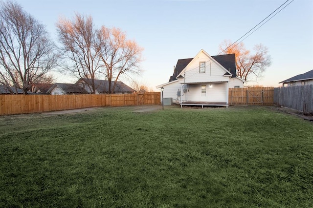 yard at dusk featuring a wooden deck and a fenced backyard