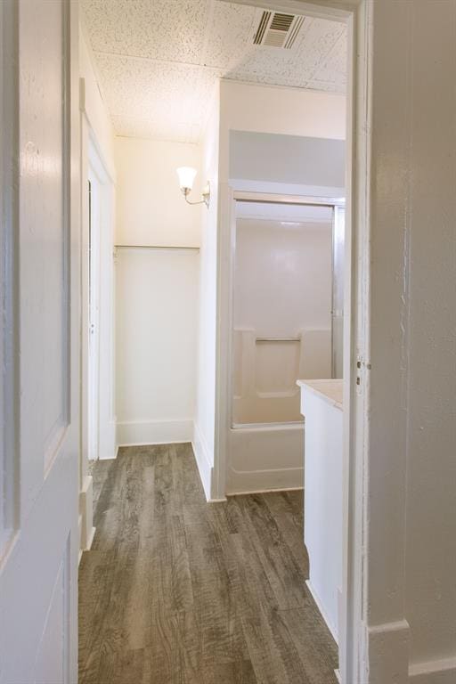 bathroom with a tub, visible vents, and wood finished floors