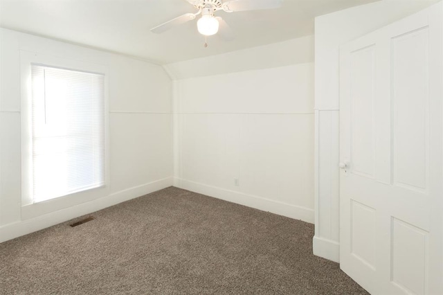 carpeted spare room featuring visible vents, a ceiling fan, baseboards, and lofted ceiling