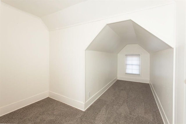 additional living space featuring baseboards, vaulted ceiling, and dark carpet