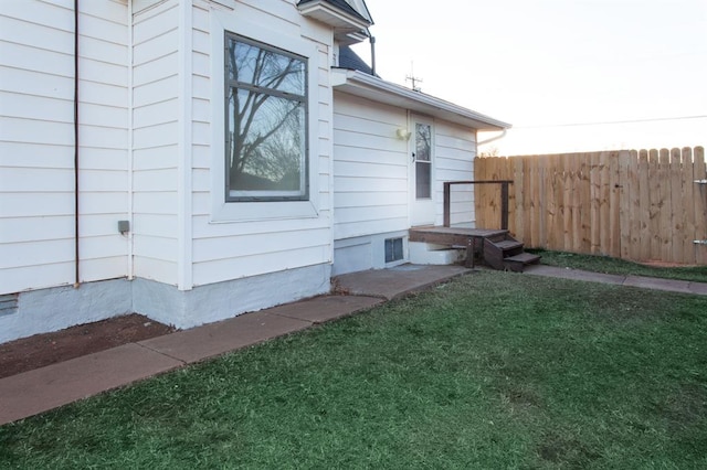 view of property exterior with fence and a lawn
