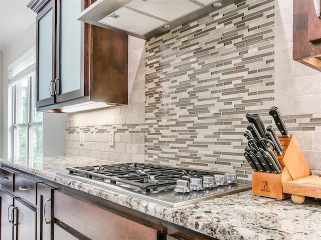 kitchen with light stone counters, decorative backsplash, and stainless steel gas stovetop