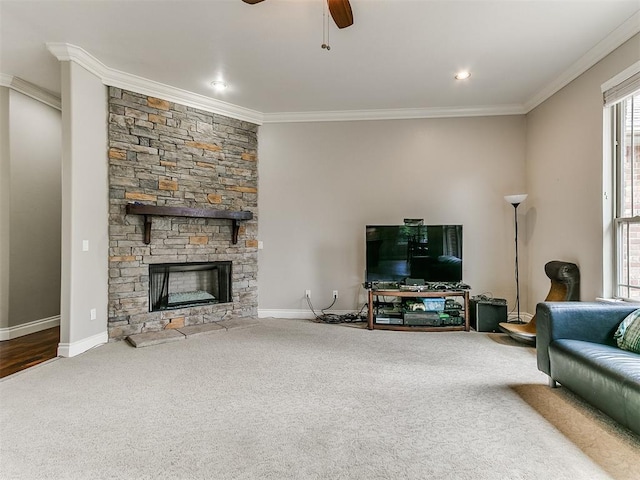 living room featuring carpet floors, crown molding, a fireplace, baseboards, and a ceiling fan