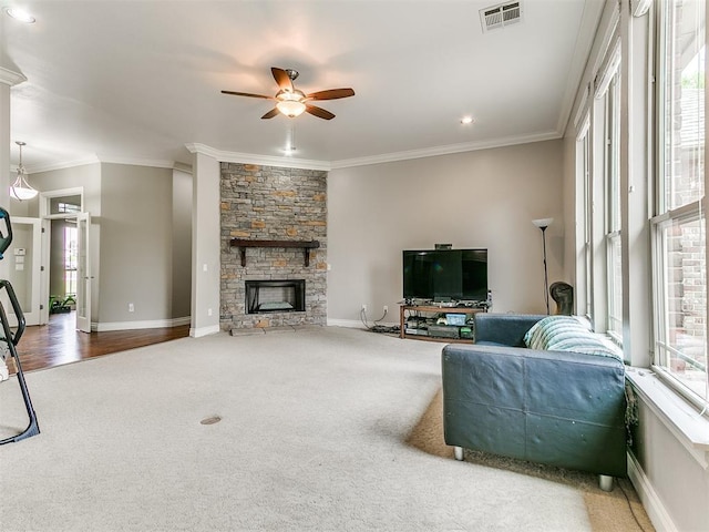 living room featuring crown molding, a fireplace, carpet, a ceiling fan, and visible vents