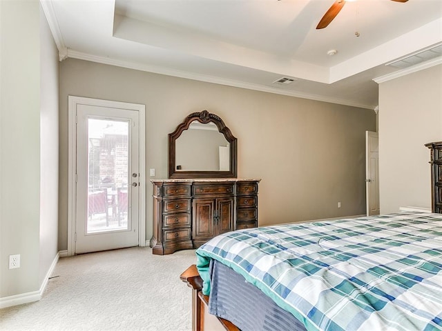 bedroom featuring visible vents, ornamental molding, a tray ceiling, and light carpet