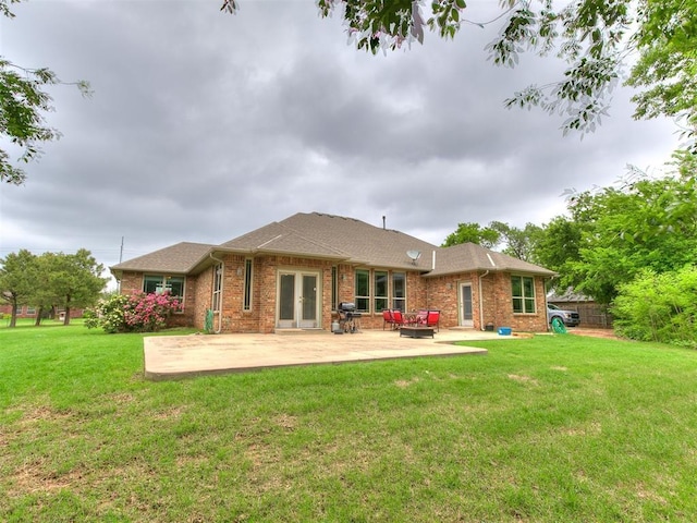 back of house featuring roof with shingles, brick siding, a patio area, french doors, and a lawn