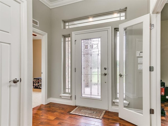 entrance foyer featuring baseboards, visible vents, ornamental molding, and wood finished floors