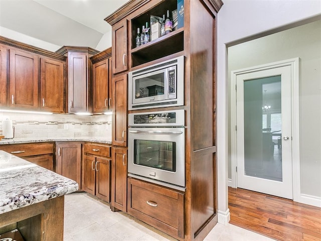 kitchen featuring tasteful backsplash, open shelves, light stone counters, stainless steel appliances, and light tile patterned flooring