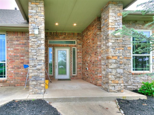 doorway to property featuring roof with shingles and brick siding