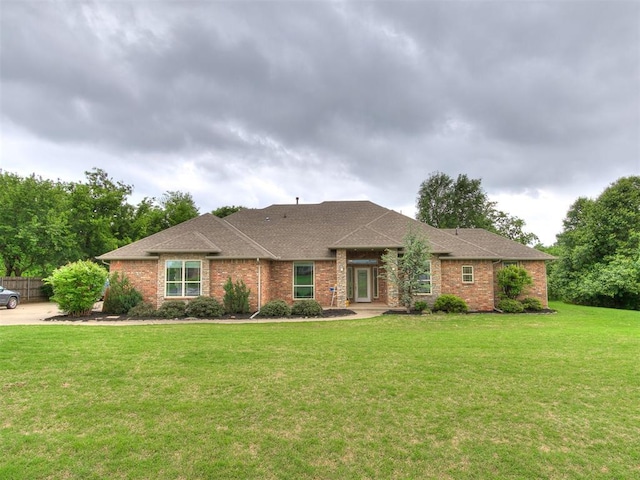 ranch-style house with brick siding, roof with shingles, and a front lawn